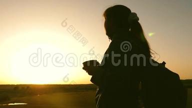 女旅行者<strong>站在山顶</strong>上喝着热水瓶里的咖啡。 旅游女孩热茶